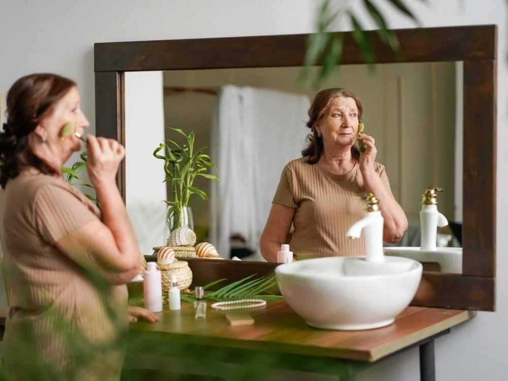 mature woman 70 years old doing facial massage. An adult woman takes care of her face, does a massage and smiles. Cosmetics and treatments for mature skin and older women, golden ag